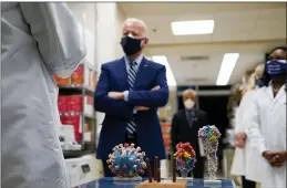  ?? EVAN VUCCI — THE ASSOCIATED PRESS ?? President Joe Biden visits the Viral Pathogenes­is Laboratory at the National Institutes of Health (NIH) in Bethesda, Md., on Feb. 11. At bottom center is a model of the COVID-19 virus.