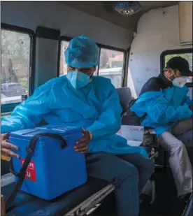  ??  ?? Nazir Ahmed, a health care worker, holds the case containing the Covishield vaccines while he and co-worker Ghulam Mohammad sit inside an ambulance June 21 as they prepare to leave for vaccinatio­n drive in Khag, southwest of Srinagar.