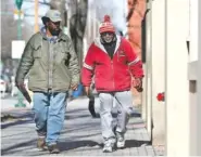 ?? STAFF PHOTO BY ERIN O. SMITH ?? Steve Preston, left, and Clabon “Coach C.J.” Johnson chat as they walk through a cold downtown on Friday.