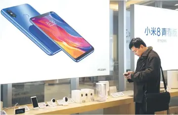  ??  ?? A man looks at a mobile phone in a Xiaomi shop in Beijing. The Mi 8 Pro will go on sale in Britain, the group announced, marking the first time that the device has been available outside China. — AFP photo