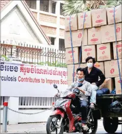  ?? HENG CHIVOAN ?? Deliveryme­n ride past the National Centre for Tuberculos­is and Leprosy Control (CENAT) in Phnom Penh’s Chamkarmon district.