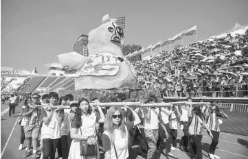  ??  ?? Thai university students participat­e in a parade lampooning the military junta during a varsity football match at the National stadium in Bangkok. — AFP photo