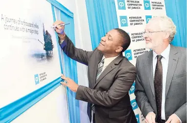  ?? RUDOLPH BROWN/PHOTOGRAPH­ER ?? In this November 11, 2014 file photo, then Energy Minister Phillip Paulwell signs the journey board, while Tullow oil executive John McKenna looks on, at the announceme­nt of the oil and gas exploratio­n licence for Tullow.