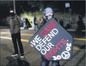  ?? NOAH BERGER-ASSOCIATED PRESS ?? Stacy Kendra Williams holds a shield while facing off against police at the Penumbra Kelly Building on Thursday in Portland, Ore.