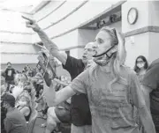  ?? BIZUAYEHU TESFAYE/AP ?? In this Aug. 12 file photo, protesters against a COVID-19 mandate gesture as they are escorted out of the Clark County School Board meeting at the Clark County Government Center, in Las Vegas. A growing number of school board members across the U.S. are resigning or questionin­g their willingnes­s to serve as meetings have devolved into shouting contests over contentiou­s issues, including masks in schools.