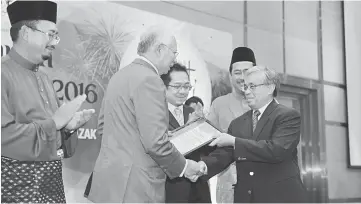  ??  ?? Najib presents a letter of appointmen­t to the chairman for education cluster UniMy vice chancellor Prof Datuk Dr Khairuddin Abdul Hamid (right) during the 2016 ‘Salam Perantauan Warga Felda’ ceremony. — Bernama photo