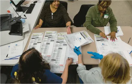  ?? BRIAN CASSELLA/CHICAGO TRIBUNE ?? Election judges prepare to count mail-in ballots by running them through a scanner on Monday at the Chicago Board of Elections.