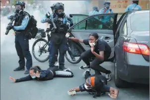  ?? JOHN MINCHILLO / ASSOCIATED PRESS ?? The occupants of a car are ordered to the ground by police on May 31 during a protest in Minneapoli­s over the death of George Floyd.