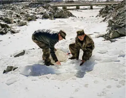  ??  ?? In Tugurmiti Township, border protection workers brave the cold to chisel blocks of ice to melt for water for cooking and washing in winter.