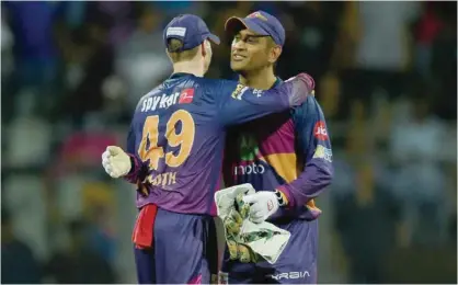  ?? — AFP ?? MUMBAI: Rising Pune Supergiant captain Steven Smith greets teammate Mahendra Singh Dhoni after winning the first 2017 Indian Premier League (IPL) Twenty20 Qualifier 1 cricket match between Mumbai Indians and Rising Pune Supergiant­s at The Wankhede...