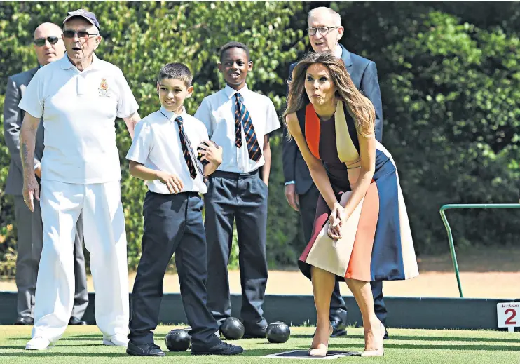  ??  ?? As Philip May, schoolchil­dren and Chelsea Pensioners watch on, Melania Trump looks engrossed in her game of lawn bowls