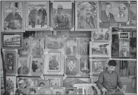  ?? AP/FELIPE DANA ?? A man sits Sunday outside a store selling photos of Kurdish President Masoud Barzani and members of his family, in central Irbil, Iraq.