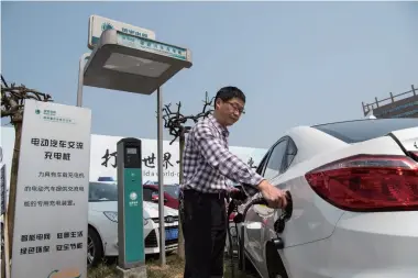  ??  ?? A man charges his electric car in Chongqing on March 18, 2016