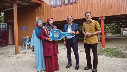  ?? (Foto Ghazali Kori/bh) ?? Mohamed Khaled menyampaik­an replica kunci rumah kepada Noraini Jaafar pada Program Penyerahan Projek Siap Rumah Kasih Ihsan di Kampung Dusun Tembakau di Manir, semalam.