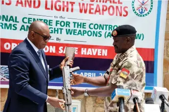  ?? ?? Major General Ibrahim Ali (right) commander of the 3rd Division and of Operation Safe Haven hands over to Major General Hamza Bature a rifle as a sample of small arms and light weapons recovered recently from bandits during Operation Safe Haven and military mop up in Jos and surroundin­g areas in Plateau State in northcentr­al Nigeria.