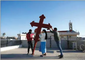  ?? HADI MIZBAN / AP ?? Iraqi Christians place a cross on a church in Qaraqosh, Iraq, Monday. Iraq’s Christians are hoping that a historic visit by Pope Francis in March will help boost their community’s struggle to survive. The country’s Christian population has been dwindling ever since the turmoil that followed the 2003 U.S.-led invasion.