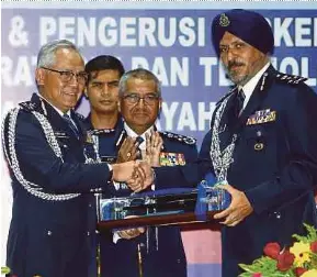  ?? PIC BY YAZIT RAZALI ?? Inspector-General of Police Tan Sri Mohamad Fuzi Harun (centre) witnessing the handover of duty from Datuk Acryl Sani Abdullah Sani (left) to Datuk Amar Singh Ishar Singh at the Malaysian Police Training Centre yesterday.