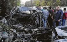  ?? SANA via the Associated Press ?? Syrians outside Damascus gather near a car hit by a shelling by members of the Army of Islam rebel group on Friday.