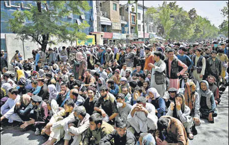  ?? AFP ?? People sit along a road outside a bank waiting to withdraw money at Shar-e-naw neighbourh­ood in Kabul.