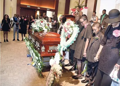  ??  ?? Family members gather around the coffin bearing the remains of Richard Vernon Sr.