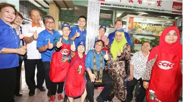  ??  ?? Abang Johari (seated second left), Tiong (third left), Dr Annuar (fourth left), Andrew (sixth left), Kong (standing behind Abang Johari, right) in a group photo with the food and drink traders at the market.