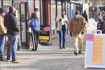 ?? Lori Van Buren / Times Union ?? A woman is seen handing out paperwork to people waiting outside Central Avenue Pharmacy where COVID-19 testing is offered on Dec. 2.