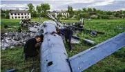  ?? AP ?? Oleksiy Polyakov (right) and Roman Voitko check the remains of a destroyed Russian helicopter in a field in the village of Malaya Rohan, Kharkiv region, Ukraine, on Monday.