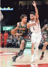  ??  ?? Hawks guard Trae Young (11) drives against Suns guard Devin Booker (1) in the first quarter at State Farm Arena on Tuesday night in Atlanta. Young scored 36 points.