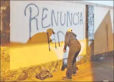  ??  ?? Un manifestan­te escribe en la muralla de la parte trasera de la casa de González Daher, exigiendo su renuncia.