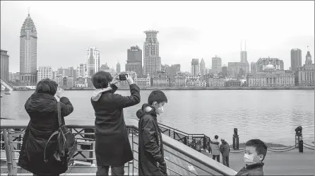  ?? GAO ERQIANG / CHINA DAILY ?? People go sightseein­g wearing masks at Shanghai’s Pudong New Area, which is usually a crowded place of interest due to its panoramic view of the Bund, earlier this month.