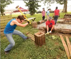  ?? Staff photos by Flip Putthoff ?? Ryan Amthauer (left) and Brent Flanagan break up rotting wood fixtures Saturday while cleaning up an area next to the trail.