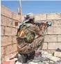  ?? YOUSEF RABIE, EPA ?? A soldier aims an automatic rifle through a peephole in a wall in Raqqa, Syria, on June 11.