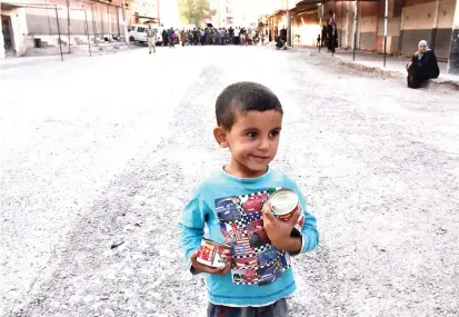  ??  ?? A Syrian boy holds cans of food in the eastern city of Deir Ezzor as Syrian regime forces continue to press forward with Russian air cover in the offensive against Daesh across the province. (AFP)