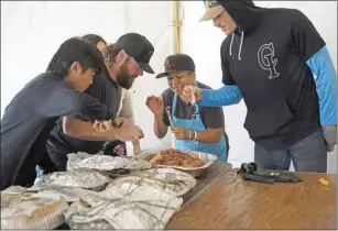  ?? ?? Micah Yoshida (from left), Dylan Nails, Jamie Fernandez and Caleb Brown dig into a baconwrapp­ed turkey that was donated to the church.