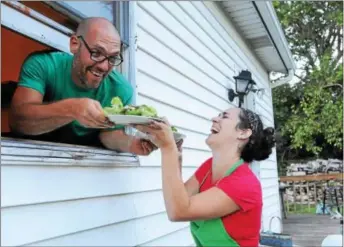  ?? DIGITAL FIRST MEDIA FILE PHOTO ?? David Ryle hands plates of fresh greens to his smiling wife Wendy during a harvest dinner held out in the field at their home. Eating healthy foods such as vegetable can lead to more positive feelings.