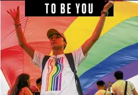  ??  ?? A volunteer helps arrange a huge rainbow flag.