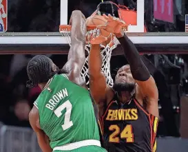  ?? KEVIN C. COX/GETTY IMAGES ?? Boston’s Jaylen Brown dunks over Atlanta’s Bruno Fernando during the third quarter on March 28 at State Farm Arena in Atlanta, Ga.