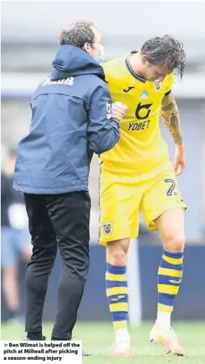  ??  ?? > Ben Wilmot is helped off the pitch at Millwall after picking a season-ending injury