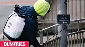  ??  ?? On the button: Disinfecti­ng a crossing signal near reopened shops DUMFRIES