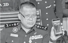  ?? - Bernama photo ?? Kamarulzam­an showing the photo of the suspect at a press conference yesterday.