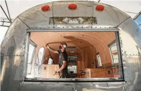  ??  ?? Carpenter Chris Witte works on custom wood walls inside an Airstream camper.