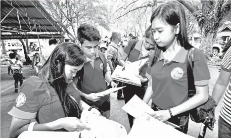  ?? MACKY LIM ?? SK CANDIDATES. Sanggunian­g Kabataan candidates from Barangay Mintal double check the entries of their certificat­es of candidacy before submitting it to the Commission on Election Office yesterday morning at Magsaysay Park in Davao City.