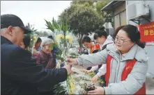  ?? GE CHUANHONG / FOR CHINA DAILY ?? Volunteers distribute flowers as they promote a more modern and civilized tomb sweeping in Hefei, Anhui province, on March 26.