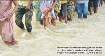  ??  ?? Indian flood victims wade through flood waters to collect relief materials in Chitnan village, west of Kolkata last month. – AFP file photo