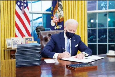  ??  ?? US President Joe Biden signs his first executive order in the Oval Office of the White House on Jan 20, in Washington. (AP)