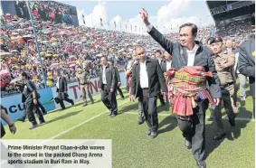  ??  ?? Prime Minister Prayut Chan- o-cha waves to the crowd in the packed Chang Arena sports stadium in Buri Ram in May.