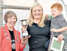  ??  ?? Top grower Elaine Lewis, with son Connor, receives the Braehead Cup from Provost Simpson