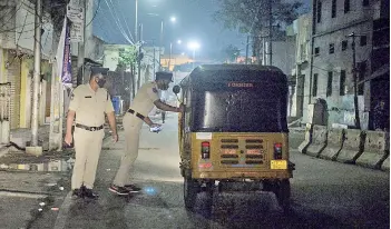  ?? — AFP photos ?? Police personnel checks an auto rikshaw along a deserted road during a night curfew imposed by the state government amidst rising Covid-19 coronaviru­s cases in Hyderabad.