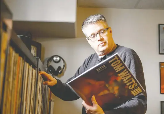  ?? MATT SMITH ?? Kevin Mitchell pulls a Tom Waits record from his collection of 3,000 records. “I say to myself: Why did this happen? Look at this wall of records. Am I crazy?”