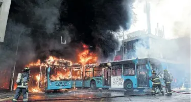  ?? Picture: MARTIN BERNETTI ?? RIOT AFTERMATH: Chilean firefighte­rs extinguish burning buses during clashes between protesters and the riot police in Santiago on Saturday